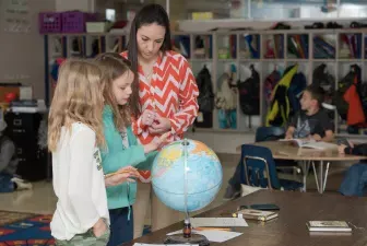 Student teacher showing students a globe of the earth